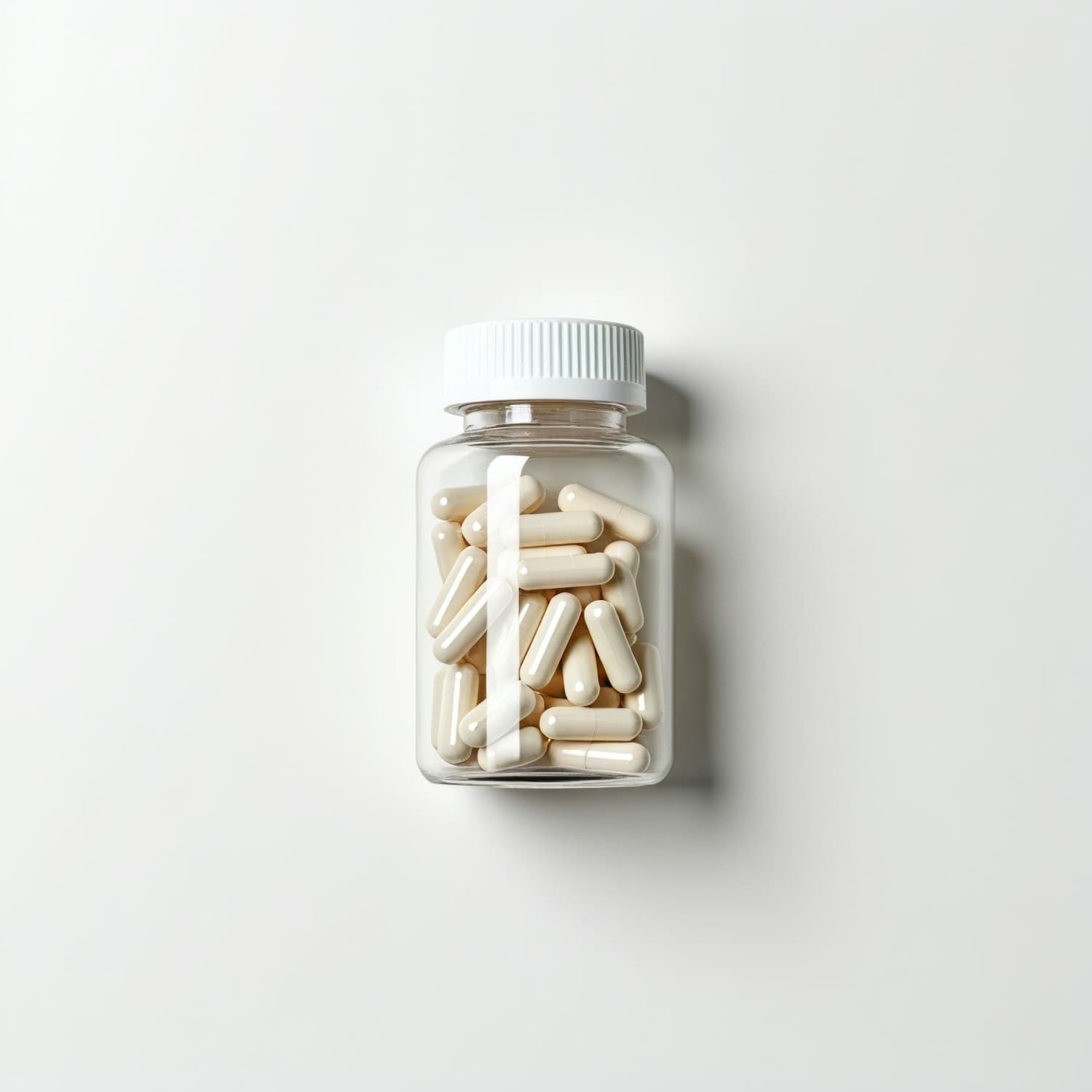 Clear supplement bottle filled with white capsules on a plain clinical background